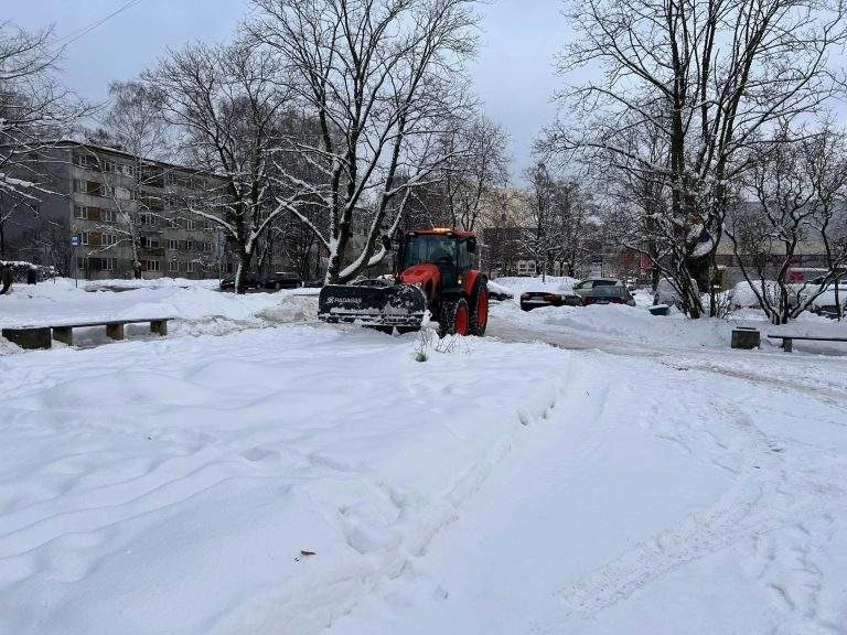 Tractor with a snow pusher clearing a snow-covered lot
